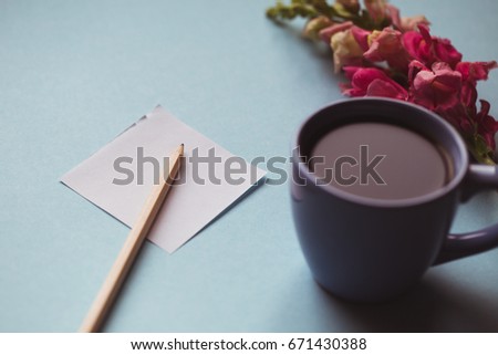 Coffee cup with spring flower and notes good morning on blue background