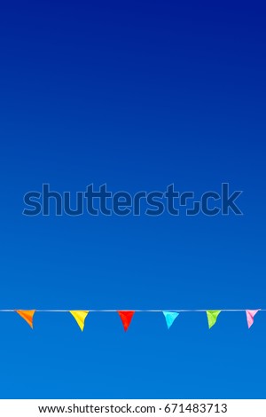 Bunting with six multicolor triangular party flags against blue sky.