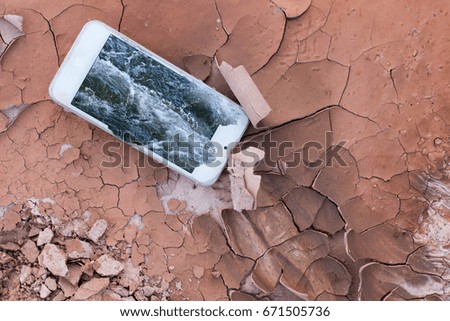 Water is flowing from the smartphone screen into the arid and cracked ground.