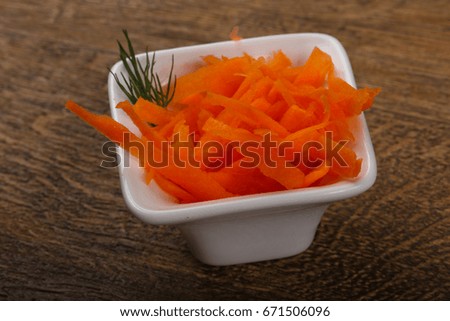 Shredded carrot heap in the bowl over wooden background