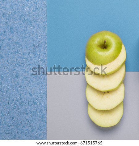A green apple cut into rings on a geometric color background. Healthy beauty concept. Object photography.