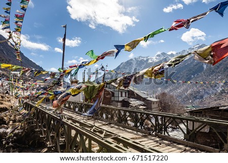 Wooden bridge over frozen river with Tibetan prayer flags with Black mountain with snow on the top is background at Thangu and Chopta valley in winter in Lachen. North Sikkim, India.