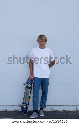 cute teenager boy stand up with skate board on city
