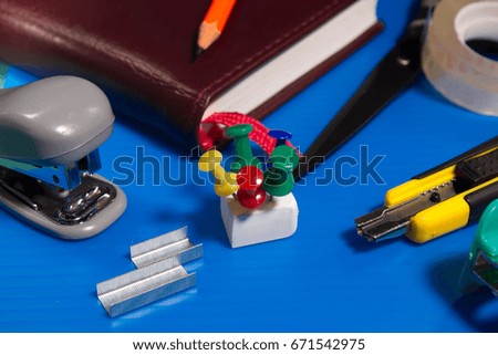 Stationery on a blue background, eraser, buttons, paperclips, ruler, clamp, stapler, sharpener