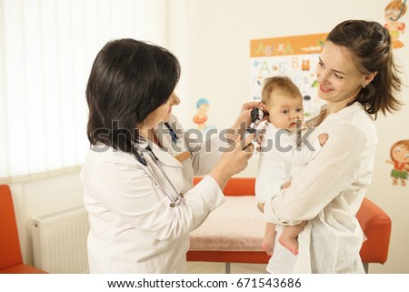 Mother looking at a doctor while she is examining baby's ear
