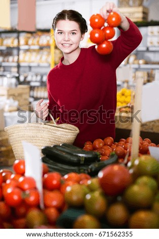 Young happy girl  buying   tomatoes  at market