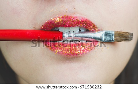 concept shoot with a beautiful Indian model with red lips holding a painting brush in between her teeth at a studio