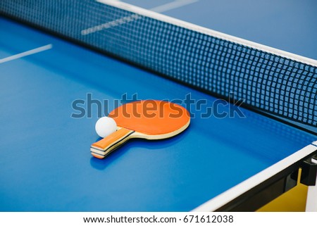 Table tennis racket and ball on blue table