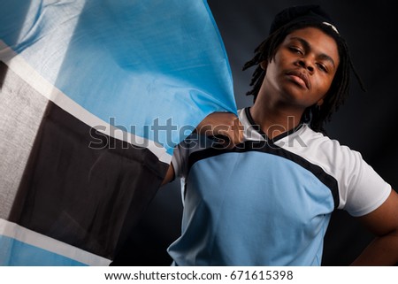 African man from Botswana with a flag smiling in a photo studio against a dark background happy