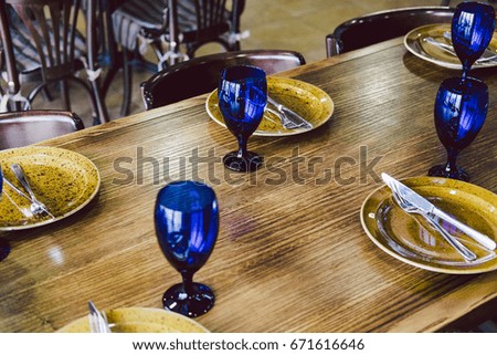 Serving banquet tables  in Empty restaurant in blue and brown sea style. Glasses, fork, knife served for dinner in restaurant with cozy interior. 