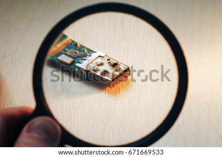 Rusty Outdated USB Flash Drive Connector on Wooden Background trough Magnifying Glass Illustrating the End of the Warranty Period of Electronic Device or Repair