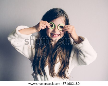Little girl with cucumbers on her face, concept of  beauty and health