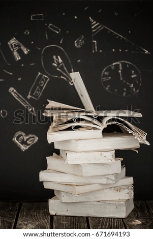 Back to school, stack of books and school supplies on blackboard background painted with chalk,education concept