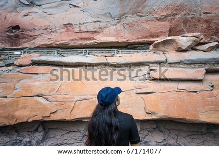 Asian woman travel and discover the prehistoric art painting of Pha Taem National Park in Ubon Ratchathani province of Thailand.