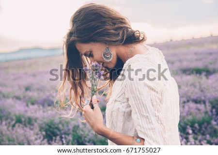 Beautiful model walking in spring or summer lavender field in sunrise backlit. Boho style clothing and jewelry. Royalty-Free Stock Photo #671755027