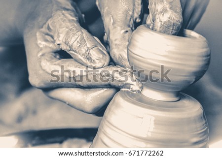 Photo in old vintage style. A man with his hands dub wall jug, which he sculpts out of clay on a circle. Create clay vessel. Modeling white-clay, shaping vessel.