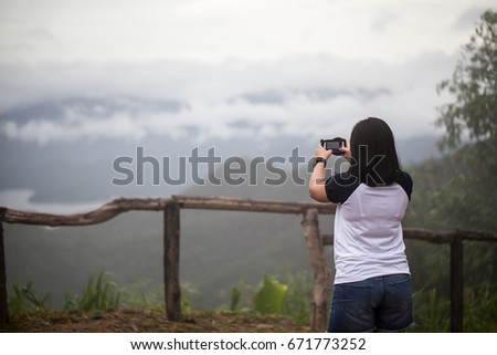 Girl tourist taking photo with phone of a forest and mountain