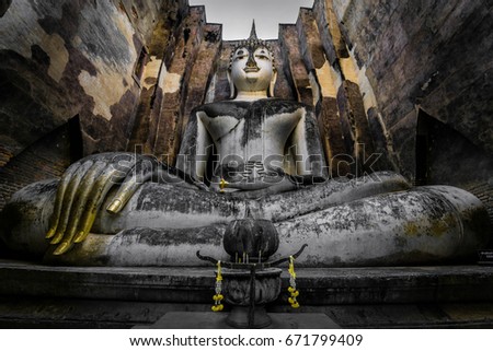 Wide angle portrait of a Big Buddha Stone and bronze Statue sitting in the calling to Earth position or Earth touching Buddha in an ancient temple in Thailand. Buddhist inner peace background.