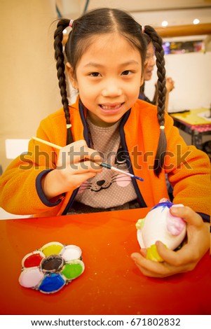 little girl sat coloring plaster doll