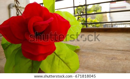 Closeup Artificial red rose flower with dark shed background on wood