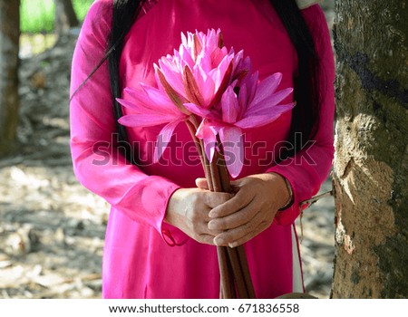 An Asian woman in traditional dress and conical hat with waterlily flowers.