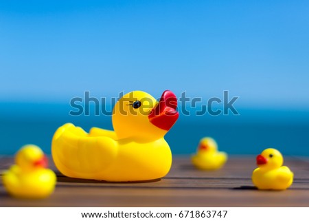Rubber toy mother duck with blurred childs against the sea - travel care concept