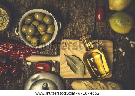Extra virgin olive oil, green olives and food ingredients on old wooden table. Royalty-Free Stock Photo #671874652