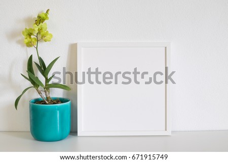 mock up frame photo with yellow orchid flower on white table in room 