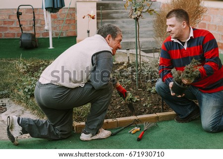 Young neighbour helps senior men with gardnering work around the house Royalty-Free Stock Photo #671930710