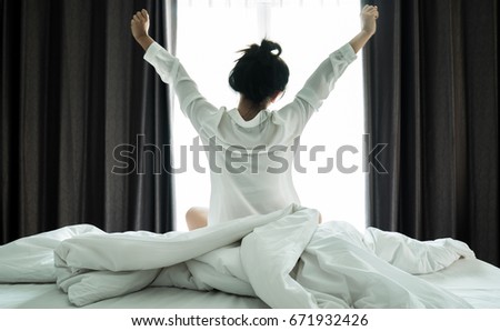 Asian women wake up from sleep. are  stretch herself  in the morning on the weekend sit on the bed at luxury room in Relax and weekend concept Royalty-Free Stock Photo #671932426