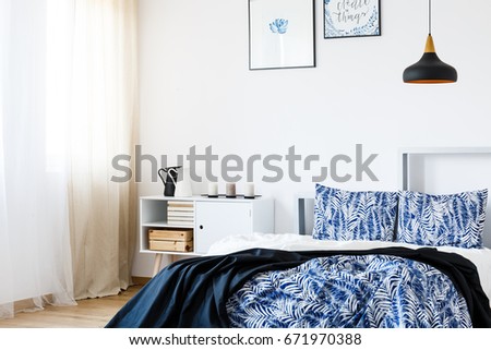 Navy blue blanket on white bed in stylish bedroom