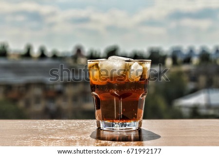 A glass of cola on the background of a modern city. Mystical still life