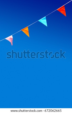 Bunting with four triangular party flags against blue sky.