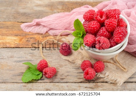 Red raspberries in bowl on grey wooden background.  Copy space