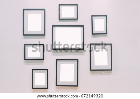 A bunch of empty black picture frames on white wall.
