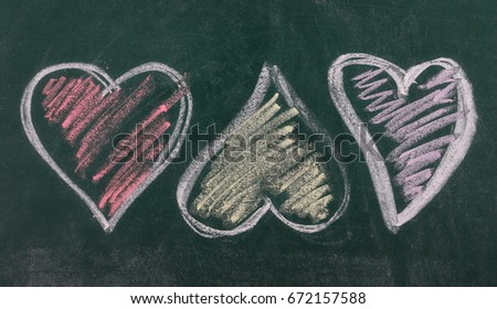 Three different colored hearts on chalkboard, blackboard texture