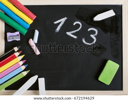 School supplies on wooden frame blackboard with 123 word and empty surface. Plasticine, chalk, sharpener, crayons and eraser.