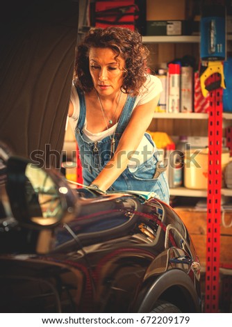 beautiful woman car mechanic in jeans overalls adjusts car engine. instagram image filter retro style