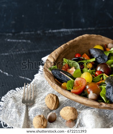 Close-up of an elegant salad of mixed wild herbs, cherry tomatoes, English slices of cucumber and walnuts
