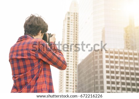 Young asian hipster on background of Thailand city . Taking photo while traveling in city during vacation.