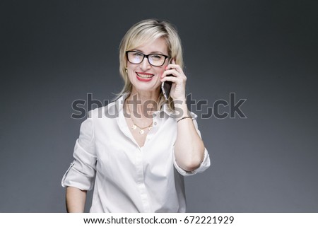 Beautiful stylish caucasian stylish woman using smartphone mobile phone talking about it on white isolated background gray. Business Concept.