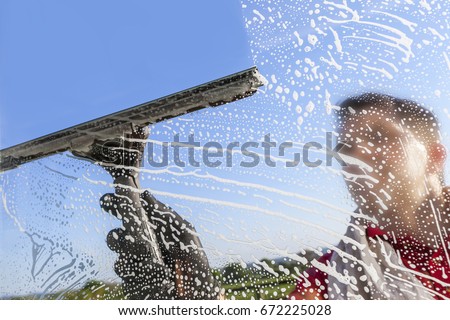 Washing and cleaning the window with a squeegee Royalty-Free Stock Photo #672225028