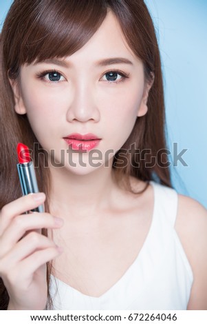 beauty woman take lipstick on the blue background