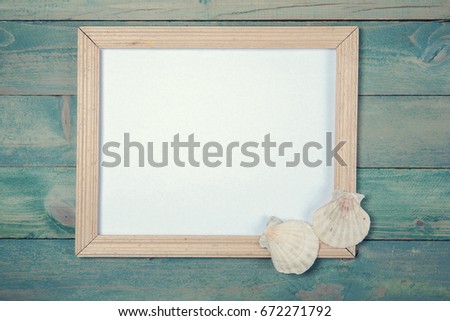 Blank photo frame with sea shells on wooden background