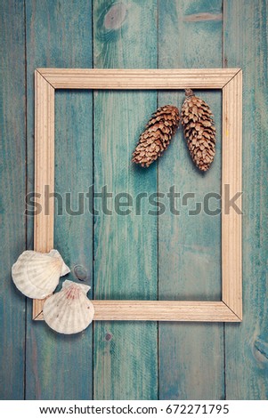 Photo frame with two pine cones and sea shells on old wooden background