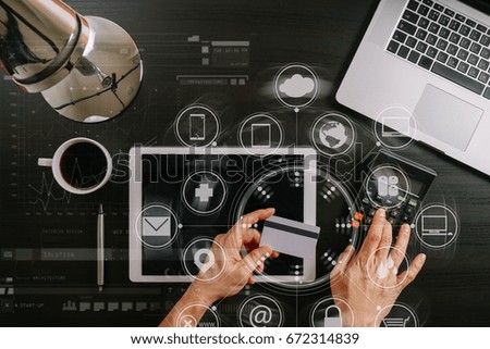 Internet shopping concept.Top view of hands working with laptop and credit card and tablet computer on dark wooden table background with Vr diagram