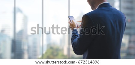 Business man using smart phone on window with city building background and copy space. Royalty-Free Stock Photo #672314896