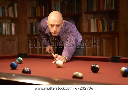 Handsome man playing pool billiards in home