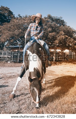 Pretty Asian woman cowgirl riding a horse outdoors in a farm for relaxing.