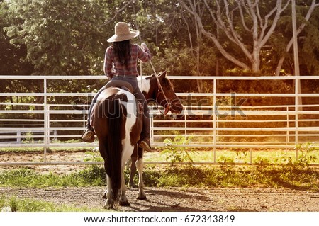 Pretty Asian woman cowgirl riding a horse outdoors in a farm for relaxing.